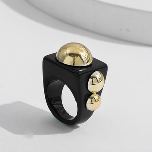 Detail of Y2K resin ring featuring a black square band and polished gold metallic spheres