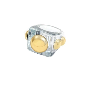 Macro shot of wide transparent resin ring with four gold hemispherical metal rivets