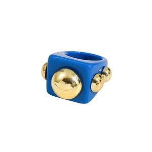 Macro detail of Y2K square blue resin ring with metallic gold bead accents