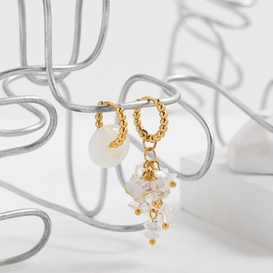 Detail of asymmetric Y2K earrings with gold beads, white stone and irregular quartz