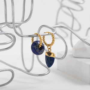 Detail of asymmetrical gold beaded earrings with blue lapis lazuli geometric pendants