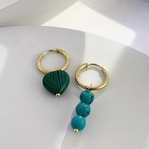 Gros plan de boucles d'oreilles asymétriques avec cœur en malachite et perles turquoise