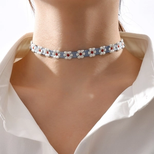 Close-up van blauwe denim choker met witte geborduurde madeliefjes rond de halslijn
