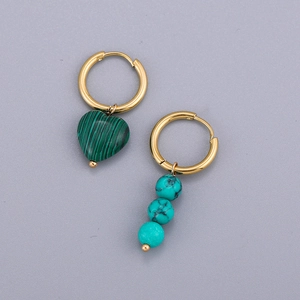 Détail de boucles d'oreilles dorées asymétriques avec malachite en cœur et perles turquoise