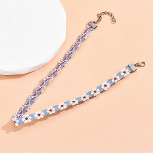 Detail van lichtblauwe kanten choker met madeliefjes borduursel en zilveren sluiting