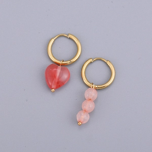 Vue détaillée de boucles d'oreilles dorées asymétriques avec cœur rose et perles