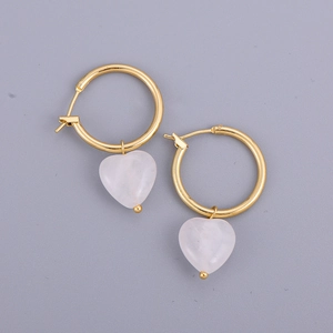 Détail de créoles dorées avec des pendentifs en cristal rose translucide en forme de cœur
