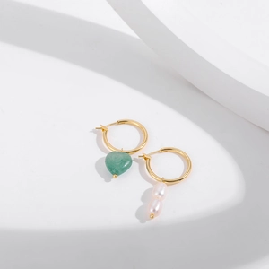 Vue détaillée de boucles d'oreilles dorées asymétriques avec cœur vert et perles roses