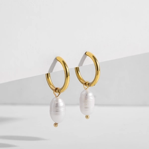 Détail de boucles d'oreilles cœur dorées avec pendentifs en perles baroques irrégulières