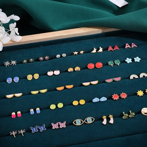 Macro shot of colorful Y2K enamel stud earrings set with butterfly and fruit motifs