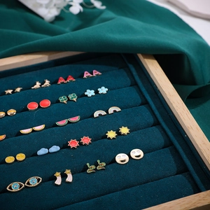 Detailed display of colorful enamel Y2K stud earrings arranged on green velvet in a wooden box