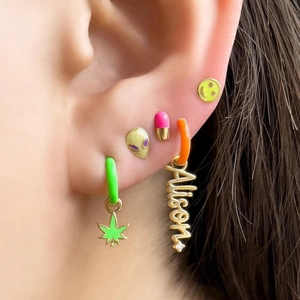 Macro shot of colorful Y2K enamel stud earrings with aliens, smiles and Alison charm