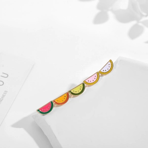 Detail of colorful watermelon enamel earrings with golden metal edges on a stone background