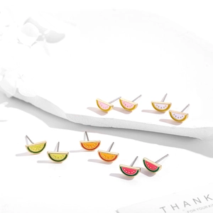 Detailed view of five pairs of colorful fruit-shaped enamel stud earrings on a stone tray