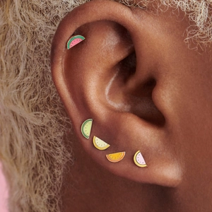 Close-up of watermelon enamel studs in five colors worn as cartilage piercings