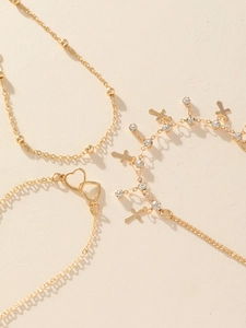 Nahaufnahme von 18K Gold-Fußkettchen mit Herzanhängern, Kreuz und glänzenden Kristallen