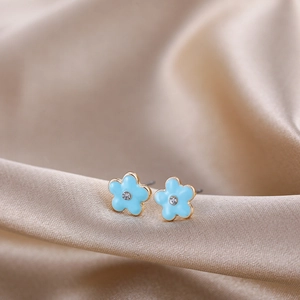 Close-up of blue floral enamel stud earrings with gold plating and zircon center