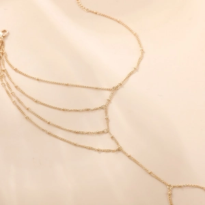 Detail der mehrlagigen böhmischen Fußkette aus 18K Gold mit Kreuz- und Herzanhängern