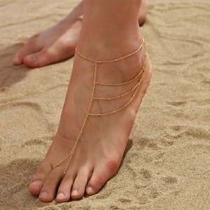 Detail einer böhmischen goldenen Schicht-Fußkette mit Perlen am Sandstrand