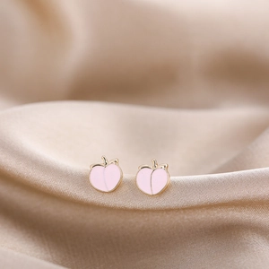 Macro shot of pink enamel peach stud earrings on a silk background for a soft aesthetic