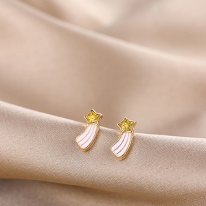 Macro shot of gold star-shaped earrings with yellow glitter and white enamel details