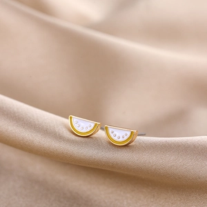 Macro shot of cute watermelon enamel stud earrings with gold finish on silk