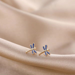 Detailed macro view of golden dragonfly earrings with deep blue enamel and metal frames