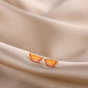Detailed close-up of vibrant watermelon enamel stud earrings on champagne silk fabric