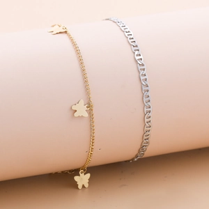 Detailaufnahme von 18K Gold Schmetterling-Anhängern und Silber Panzerketten-Fußkettchen