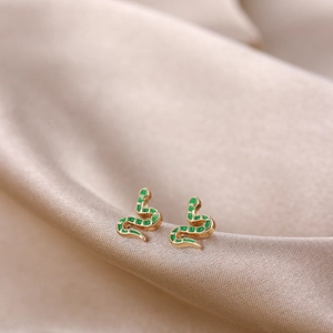 Detail of gold snake earrings with green enamel on elegant champagne silk background