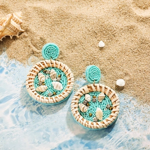 Détail de boucles d'oreilles de plage bohèmes avec perles turquoise et coquillages