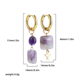 Detailed view of asymmetric earrings featuring purple natural stone and gold metal cross charms