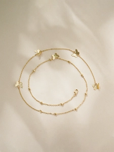 Primer plano del collar de mariposa en oro de 14K con alas texturizadas y cuentas doradas