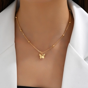Detalle de collar con colgante de mariposa de oro de 14K sobre una chaqueta blanca