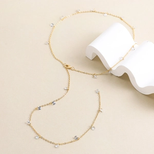 Detalle de un collar bañado en oro de 14K con colgantes de circón en soporte blanco