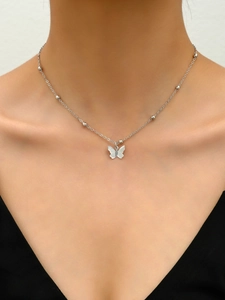 Detalle del collar con colgante de mariposa plateada con textura en la clavícula femenina