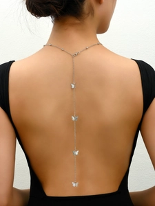 Primer plano del collar de espalda con mariposas plateadas en un vestido negro escotado