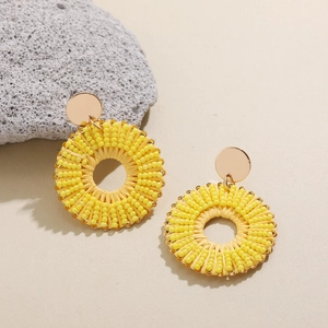Détail de boucles d'oreilles créoles jaunes avec breloque étoile de mer sur pierre