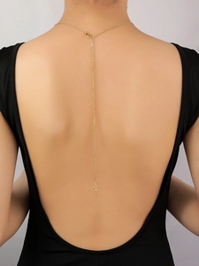 Elegante collar de espalda en oro de 14K con dos cruces sobre un vestido sin espalda