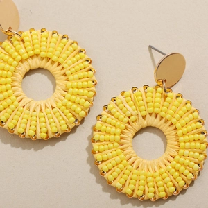 Détail des boucles d'oreilles créoles jaunes avec perles et textures de style marin