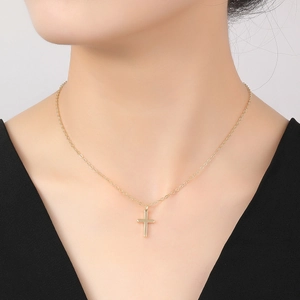 Primer plano de un collar con colgante de cruz de oro de 14K minimalista usado con cuello en V