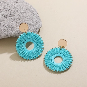Détail macro de boucles d'oreilles rondes en perles turquoise avec clous dorés