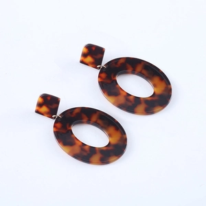 Dettaglio ravvicinato di orecchini ovali in acetato tartarugato con maglie metalliche dorate