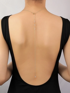 Detalle de collar para espalda en oro de 14K con cristales en un vestido negro abierto