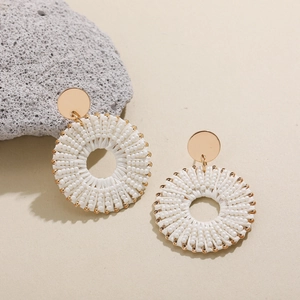 Gros plan de boucles d'oreilles bohèmes en perles blanches avec détails dorés chic