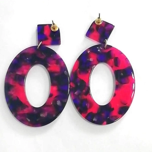 Dettaglio di orecchini ovali in acrilico con texture marmorizzata rosa e viola vivace