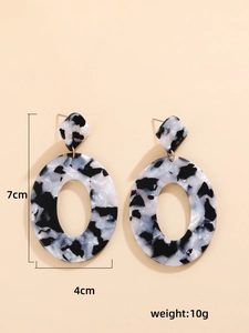 Dettaglio di orecchini pendenti in acrilico marmorizzato con dimensioni di 7 cm per 4 cm
