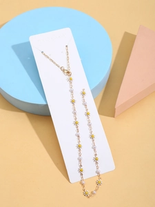 Detalle de collar de oro de 14K con colgantes de margaritas y perlas blancas en tarjeta
