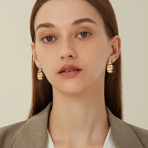 Pendientes de gota en espiral huecos de oro de 18 quilates mostrados en una modelo