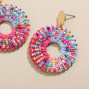 Vue macro de boucles d'oreilles bohèmes en raphia avec perles colorées et clou doré